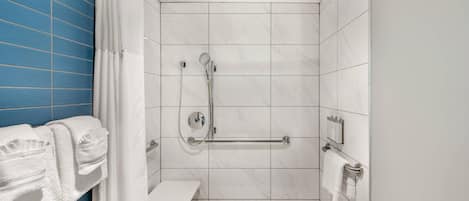 A modern bathroom with a shower, white tiles, a bench, and a towel rack.
