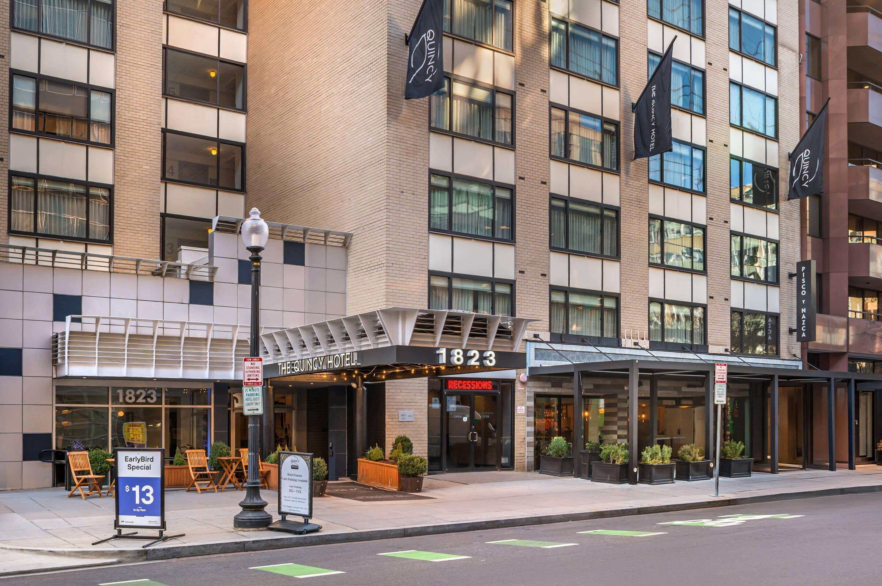 A hotel with a modern facade, numbered 1823, featuring a covered entrance and outdoor seating area.