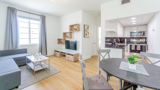 A modern apartment with a living room, dining area, and kitchen.