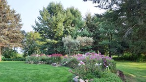 A well-maintained garden with a variety of flowering plants and trees. - Stone Road Log House (Westport)
