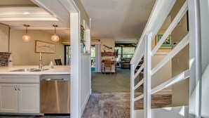 Une cuisine moderne équipée d’un lave-vaisselle, un coin repas avec une table et des chaises, et un escalier menant à un autre niveau.