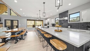 Une cuisine moderne dotée d’un grand îlot central, de tabourets de bar et d’un coin repas avec des bancs.
