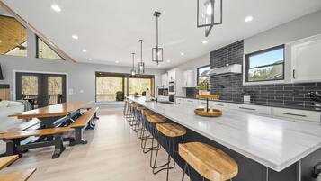 A modern kitchen with a large island, bar stools, and a dining area with benches.