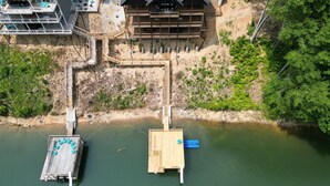 Un grand bâtiment à étages, doté d’un toit en pente, relié à une jetée qui s’avance sur une étendue d’eau calme.