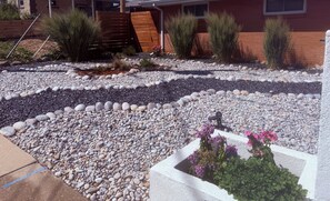 A landscaped garden with a variety of plants and a concrete planter with flowers.