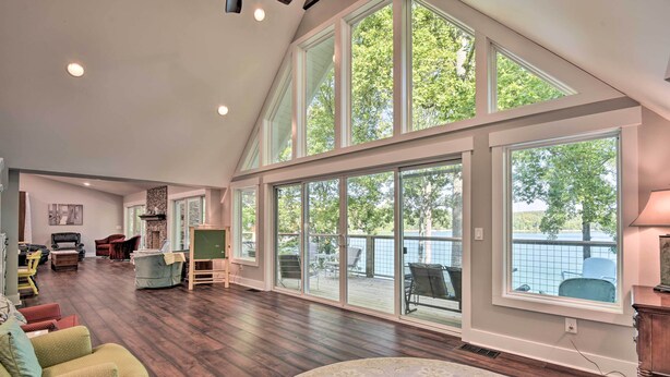 A spacious living room with a high ceiling, large windows, and a view of the outdoors. - Renovated Lakeside Home w/ Private Boat Dock! (LaFollette)