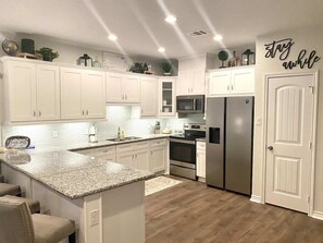 A modern kitchen with white cabinets, granite countertops, stainless steel appliances, and a central island. - NEW Build! Only Minutes from the Lake! (Montgomery)