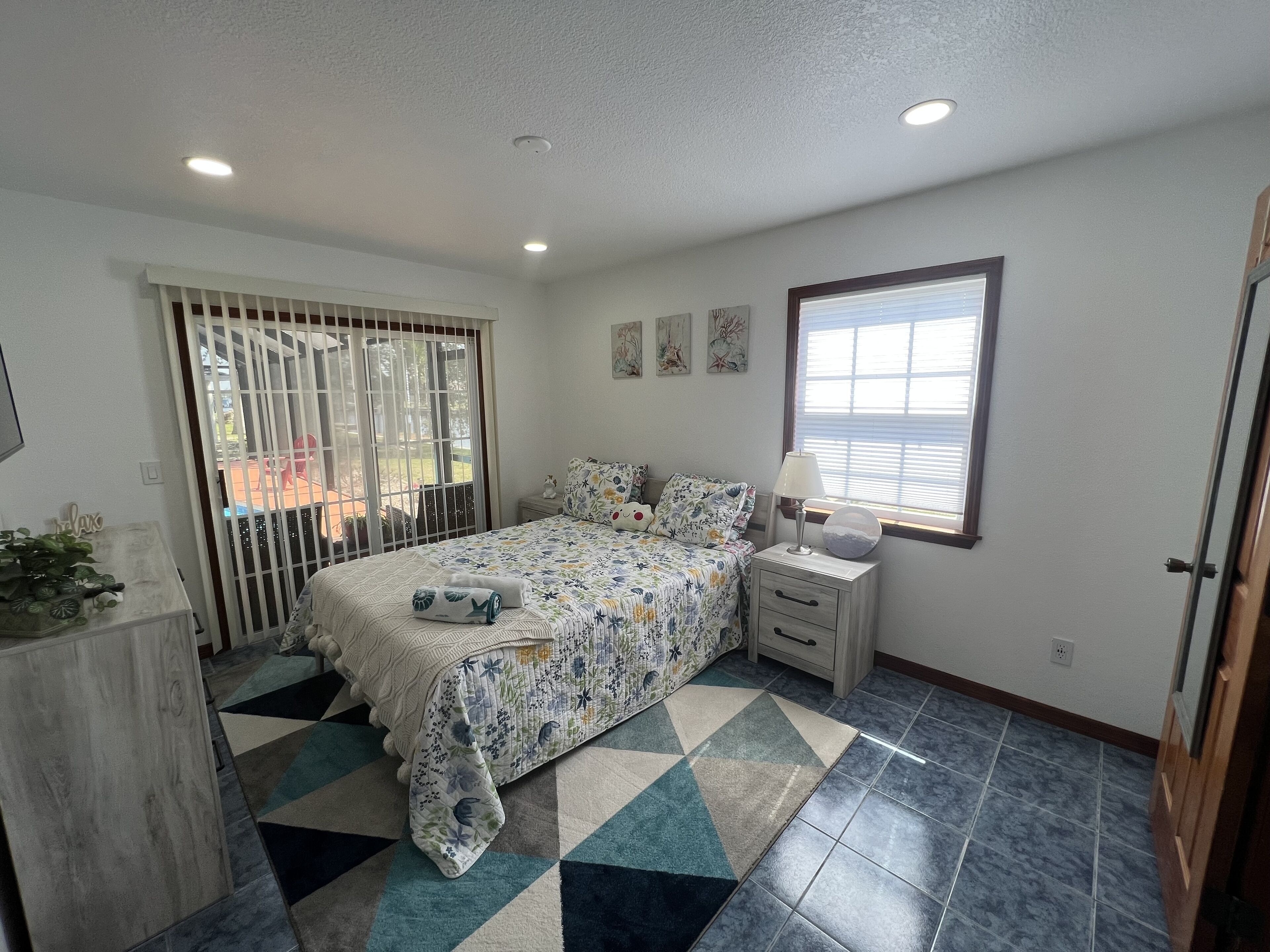 A bedroom with a bed, bedside table, lamp, and a window.
