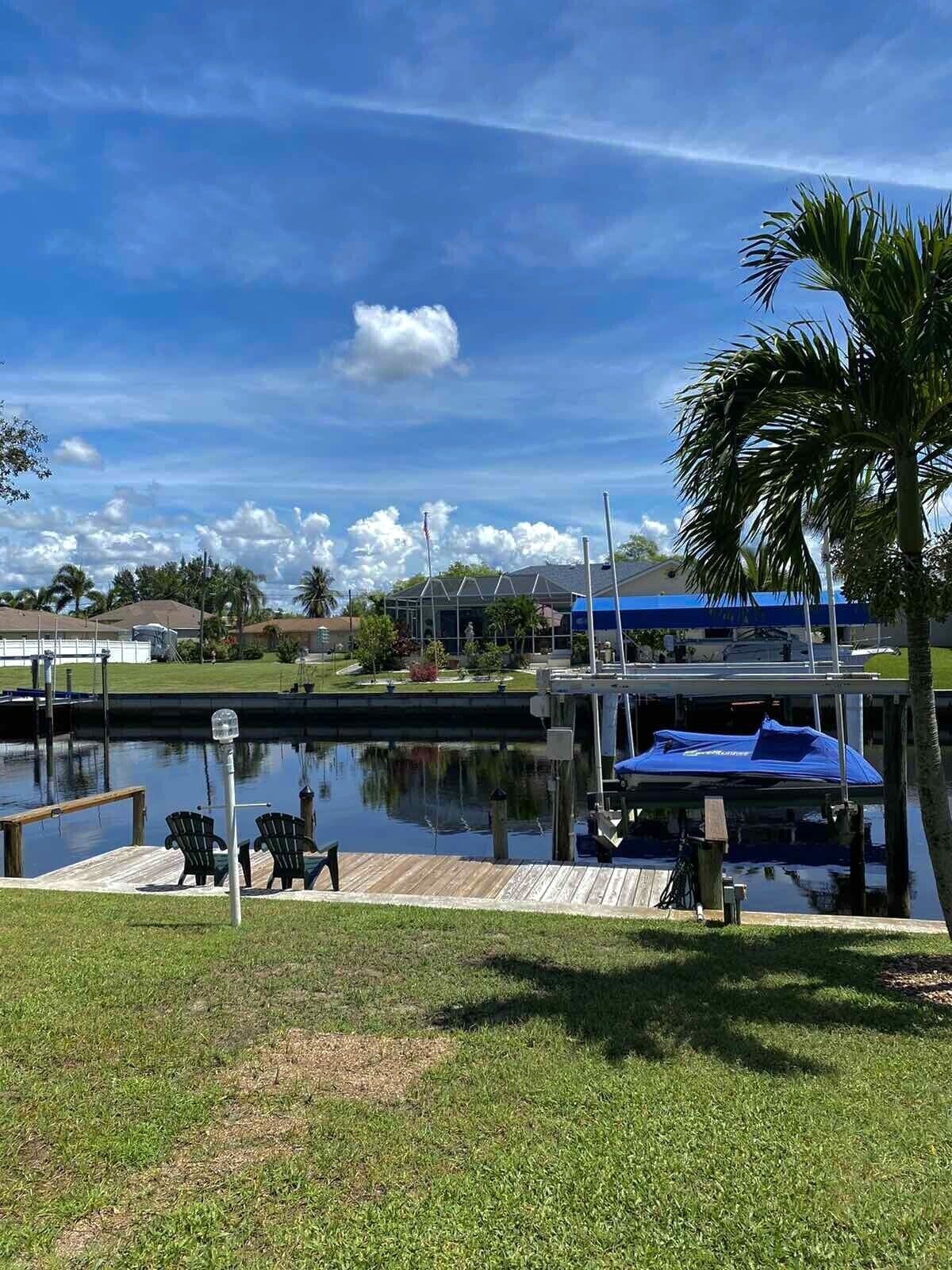 A marina with boats docked, a covered area, and a grassy area with chairs.
