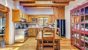 Une cuisine avec des meubles de rangement en bois, une table à manger et un buffet rouge avec des portes en verre.