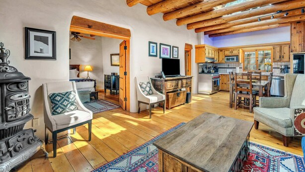 Un intérieur rustique avec des poutres en bois, une cuisine et un espace de vie doté d’une cheminée et de sièges confortables.