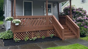Ein zweistöckiges Haus mit einer Veranda und einer Holztreppe, die zum Eingang führt.