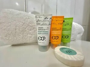 A bathroom with a white towel, three skincare products, and a bar of soap.