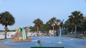 A park with a green bench, palm trees, and a playground with colorful equipment. - Studio, Private Entrance, fenced in quiet corner, pets ok, large Parking area (St. Cloud)