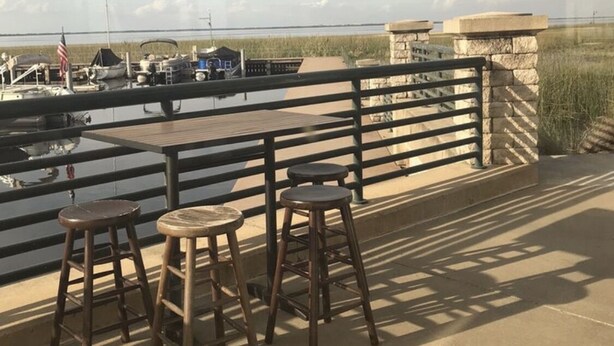 A patio with a table and stools overlooking a marina with boats and a grassy area. - Studio, Private Entrance, fenced in quiet corner, pets ok, large Parking area (St. Cloud)