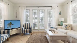 Ein Wohnzimmer mit Fernseher, einem gestreiften Sessel, einem weißen Sofa und einem Couchtisch.