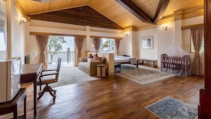 Una habitación amplia con suelo de madera, un ventanal grande, un sofá, una mesa de comedor y una silla.