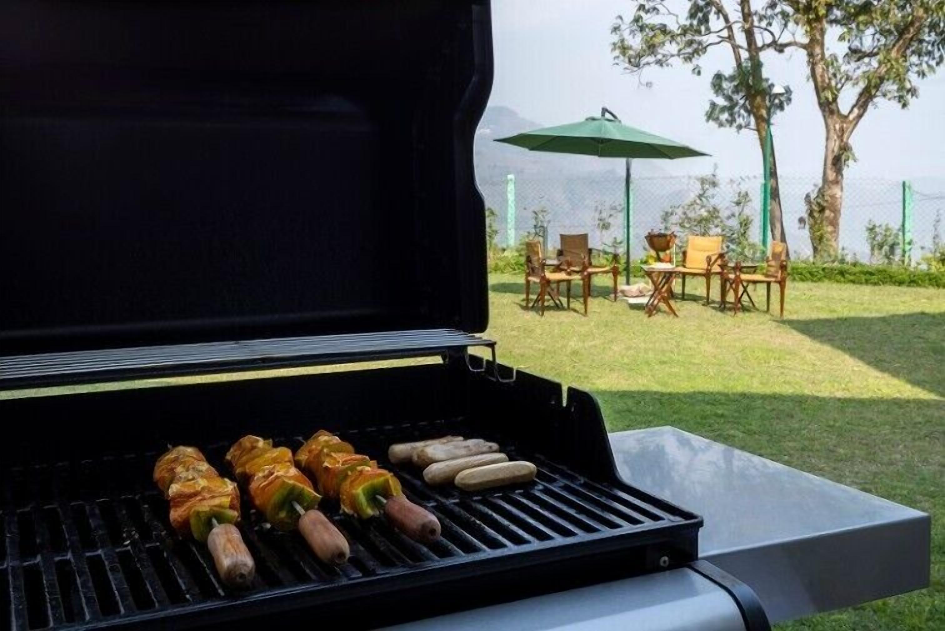 A grill with skewers of vegetables and sausages.