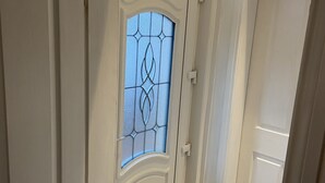 Eine weiße Tür mit einem dekorativen Glasfenster und einer kleinen Lüftung darunter.