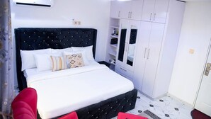 Ein Schlafzimmer mit einem großen Bett, weißen Wänden, einem schwarzen Kopfteil und einem Kleiderschrank mit Glastüren.