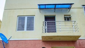 A two-story building with a balcony, potted plants, and a satellite dish. - Lovely One-Bed Apartment Located in Abuja (Abuja)