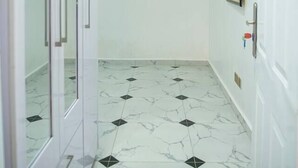 A hallway with a white tiled floor and white walls. - Lovely One-Bed Apartment Located in Abuja (Abuja)