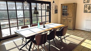 Comedor con mesa, sillas, luces colgantes y vistas amplias a través de grandes ventanales.
