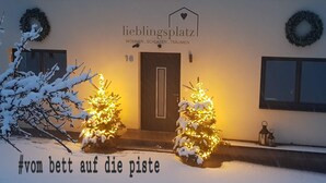 Ein Gebäude mit einem Schild, auf dem 'lieblingsplatz' steht, und zwei festlich geschmückte Weihnachtsbäume davor.