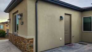 A building with a beige exterior, a stone base, and a door with a number plate.