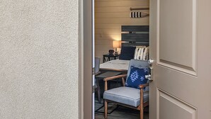 A doorway leading into a room with a ceiling fan, a bed, a desk, and a chair.