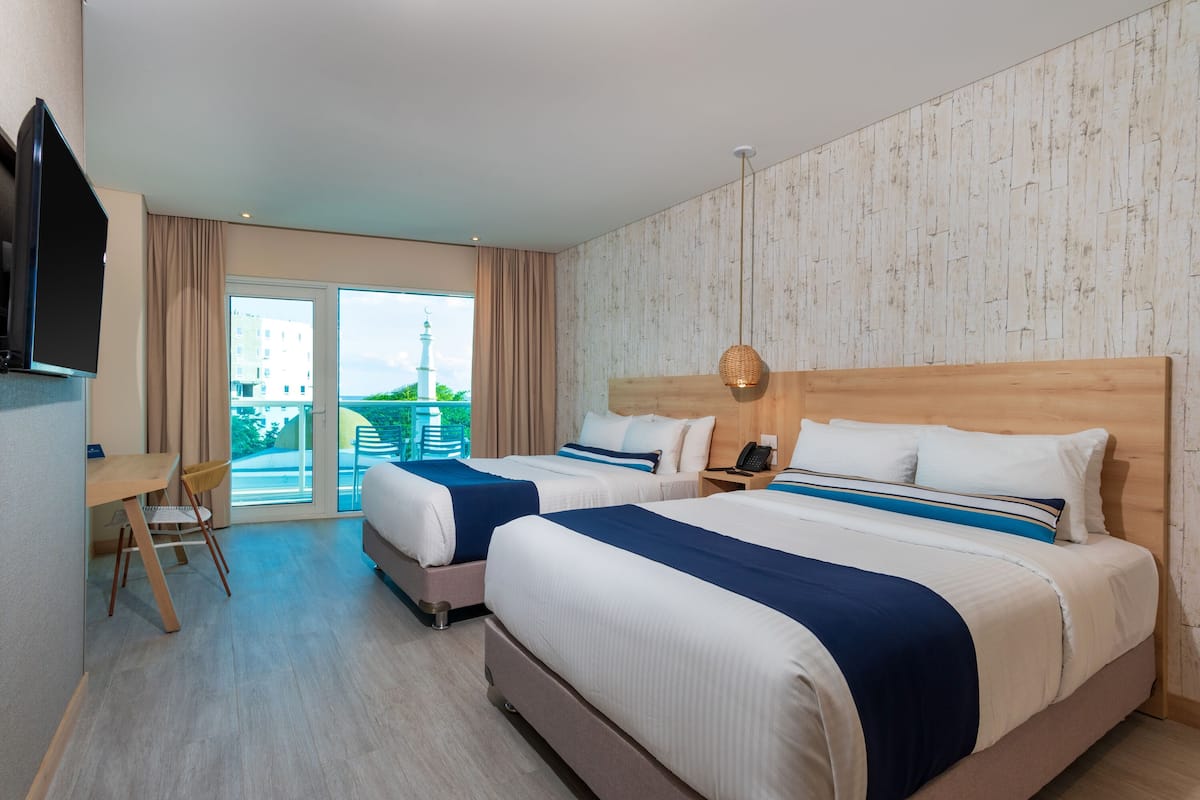 Une chambre d’hôtel avec deux lits, un bureau et une chaise.