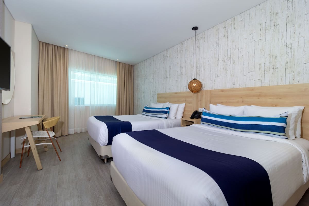 Une chambre d’hôtel avec deux lits, un bureau et une télévision.