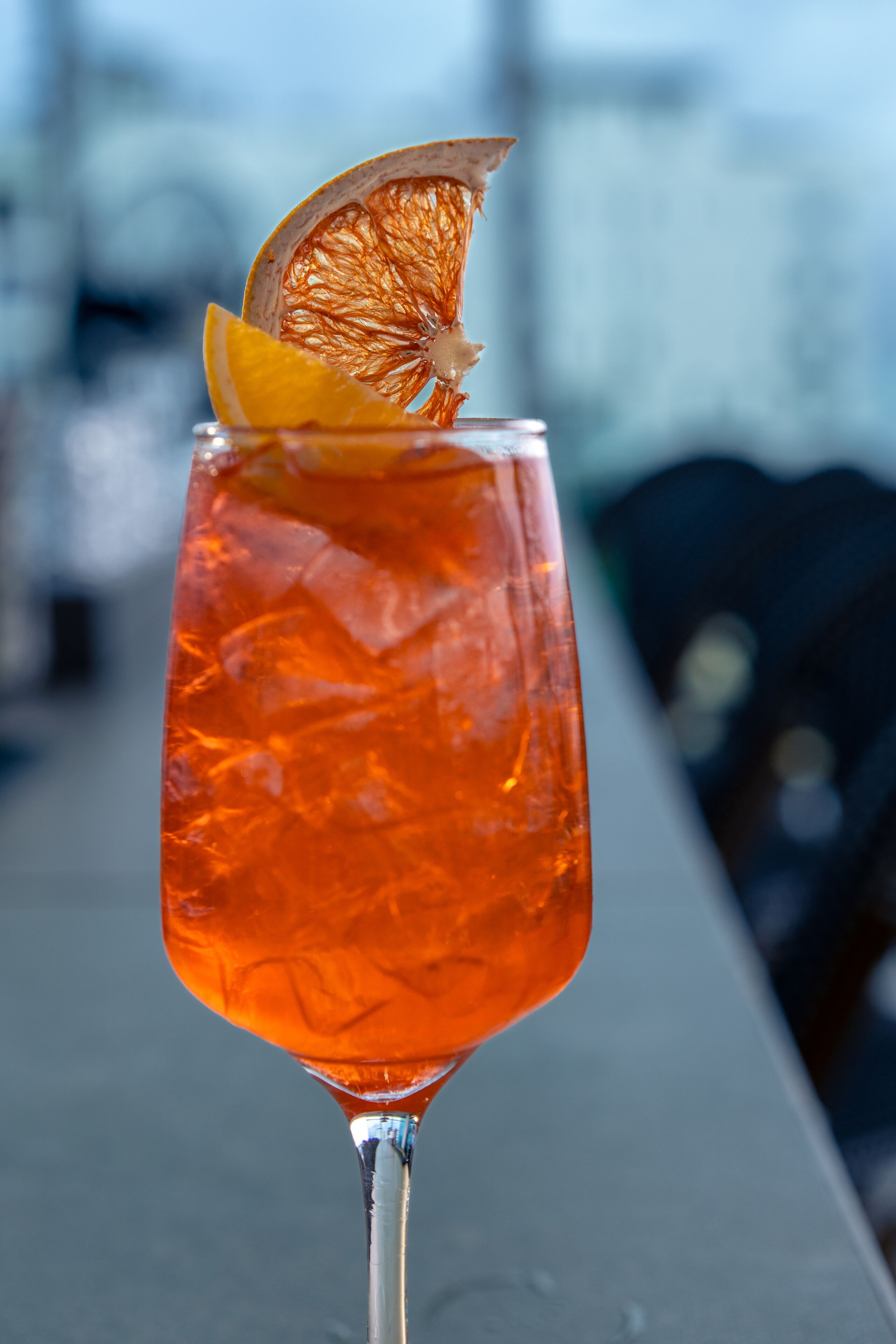 A cocktail glass with ice cubes and a slice of orange garnish on a bar counter.