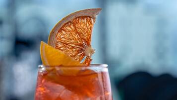 A cocktail glass with ice cubes and a slice of orange garnish on a bar counter.