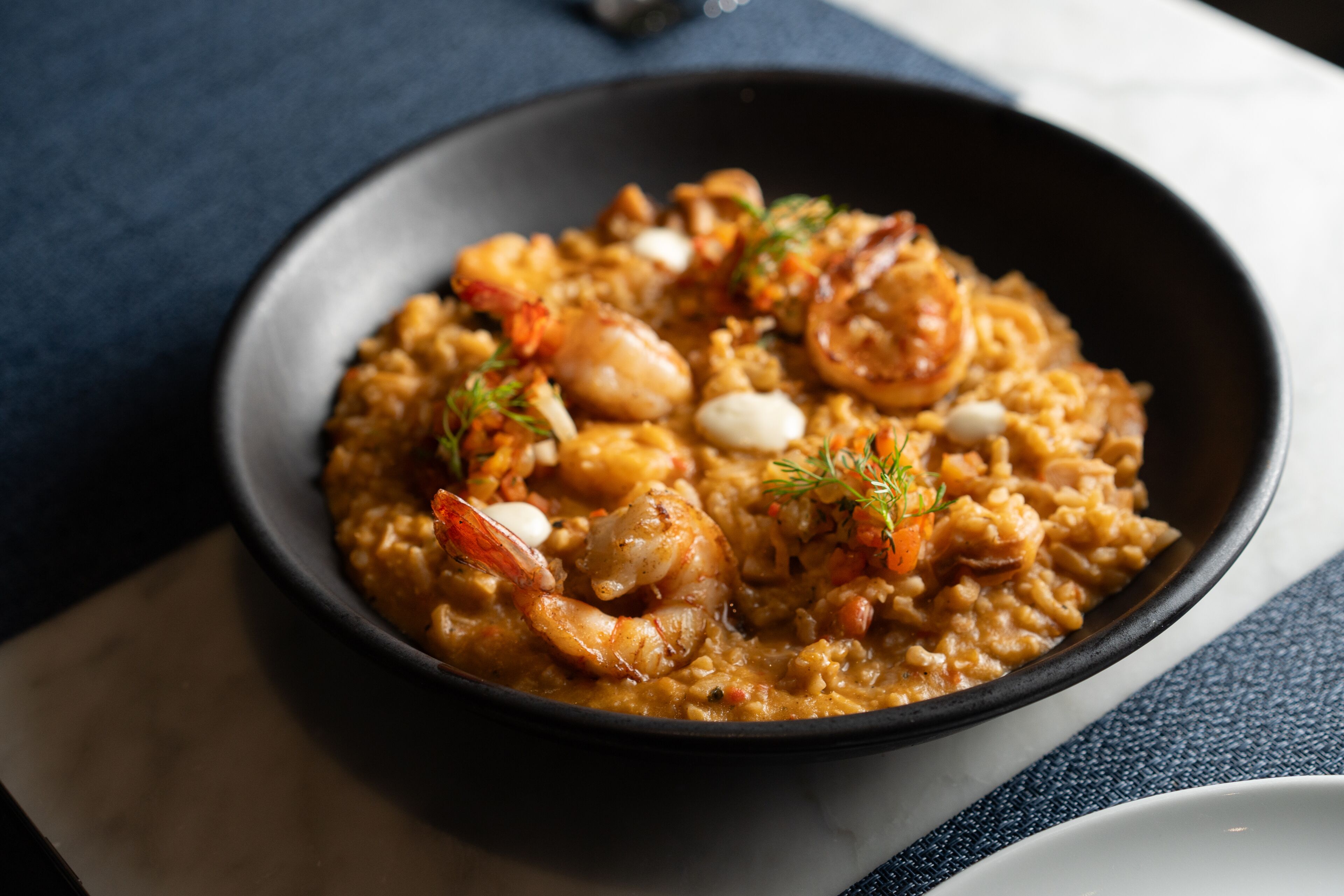 A bowl of seafood risotto with shrimp and herbs.