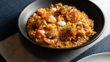 A bowl of seafood risotto with shrimp and herbs.