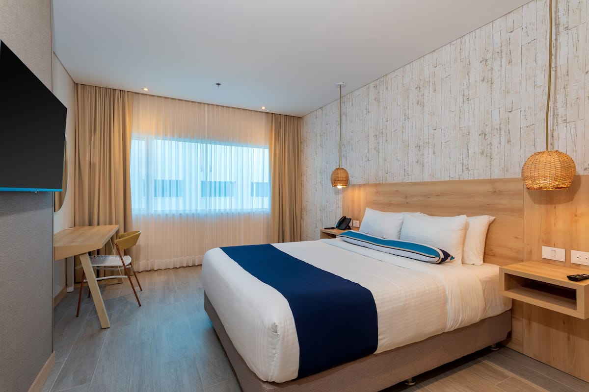 Une chambre d’hôtel moderne, dotée d’un grand lit, d’un bureau et d’une chaise.