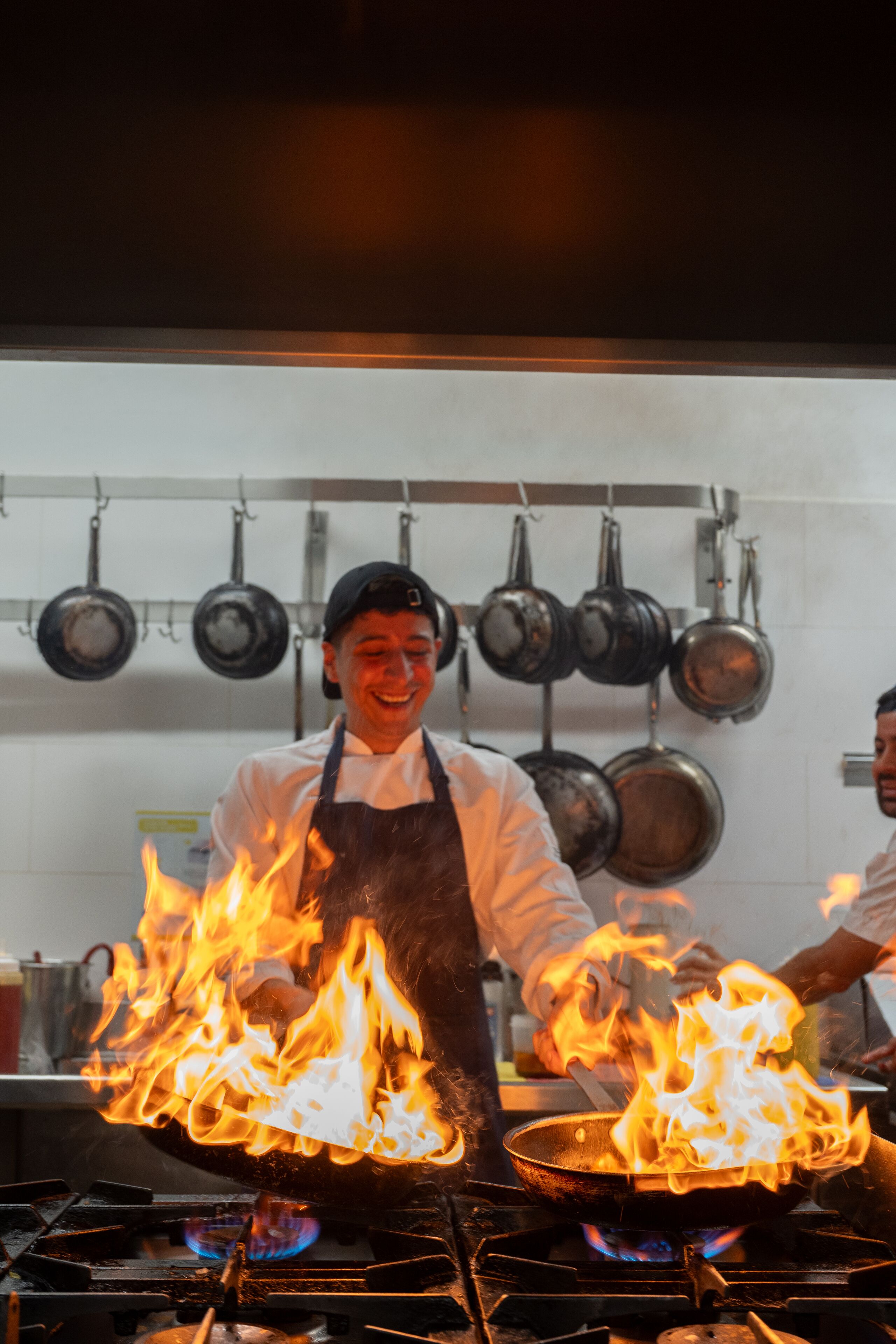 Un chef cocinando sobre llamas en una cocina.