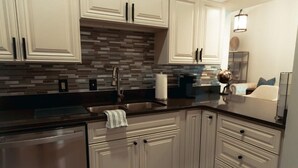 Una cocina moderna con armarios blancos, salpicadero a rayas y electrodomésticos de acero inoxidable.