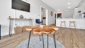 Eine moderne Küche mit einem Holzespeise Tisch, einem an der Wand montierten Fernseher und einer Kücheninsel mit Hockern.