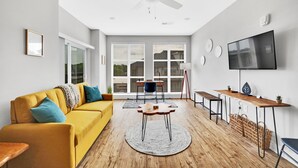 Ein modernes Wohnzimmer mit einem gelben Sofa, einem runden Couchtisch, einem Fernseher und einem Deckenventilator.
