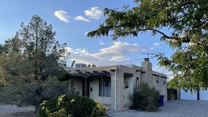 A house with a unique architectural style, featuring a flat roof, a chimney, and a gravel driveway. - Casa Bonita located 2 blocks from Old Town  (Albuquerque)