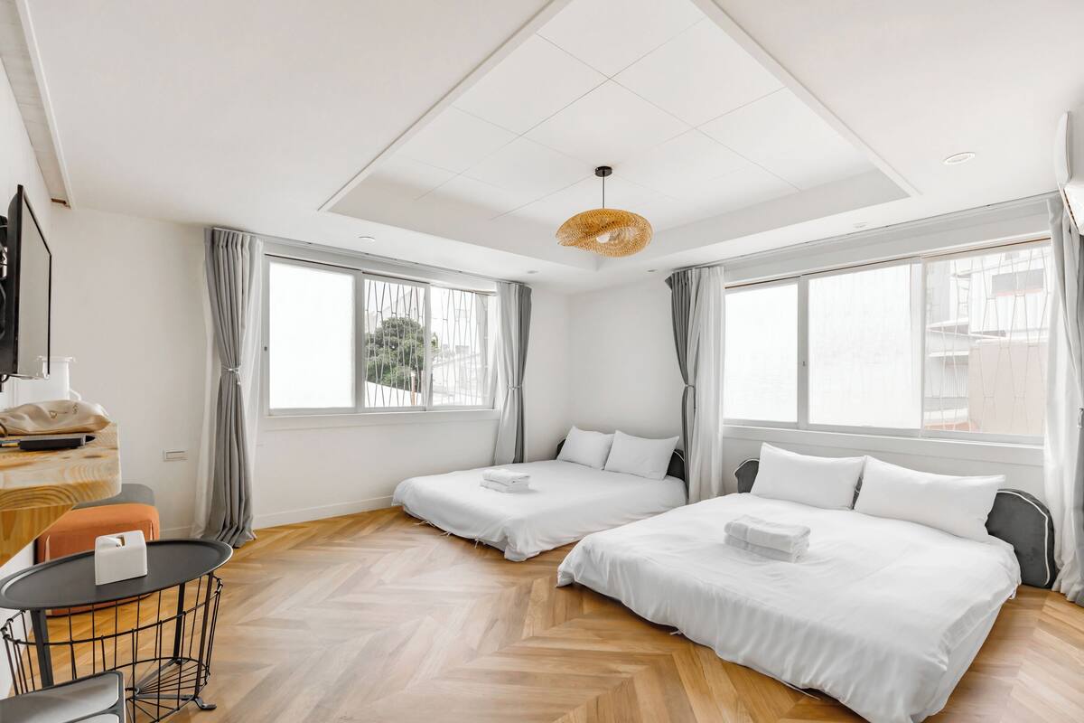 A hotel room with two beds, a small table, a chair, and a TV.