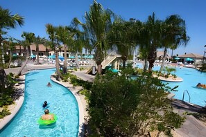 Un espace piscine d’un complexe hôtelier comprenant plusieurs piscines, des palmiers et des chaises longues.