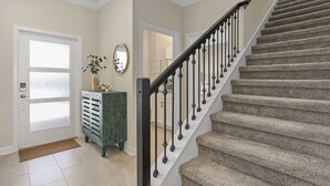 A staircase with a black handrail and white balusters, leading to an upper floor.