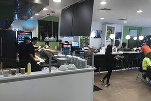 Et moderne køkken med rustfrie stål-hvidevarer, en central ø og et siddeområde med barstole.