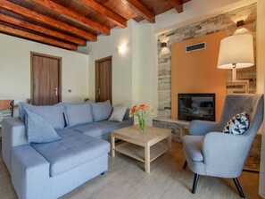 Relax in this stylish living room with a sofa, armchair, and coffee table, featuring a stone fireplace and modern TV.