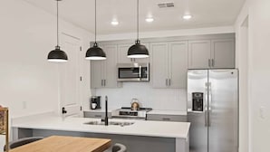A modern kitchen with a central island, stainless steel appliances, and pendant lighting.