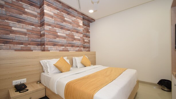 Ein Schlafzimmer mit einem hölzernen Kopfteil, einem Bett mit weißer Bettwäsche und gelben Kissen, einem Nachttisch mit Telefon und einem Deckenventilator.