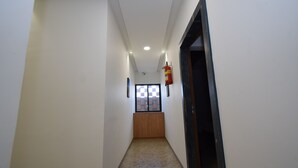 Ein schmaler Gang mit poliertem Boden, einer Holztür am Ende und einem an der Wand befestigten Feuerlöscher.